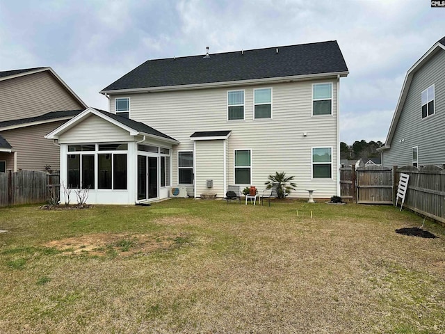 rear view of property featuring a lawn, a fenced backyard, and a sunroom