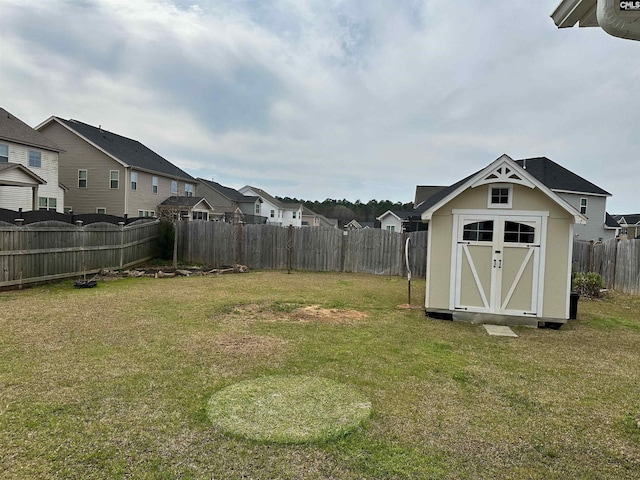 view of yard featuring an outbuilding, a residential view, a storage shed, and a fenced backyard