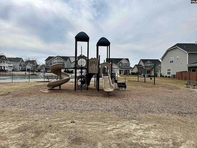 communal playground featuring a community pool, fence, and a residential view