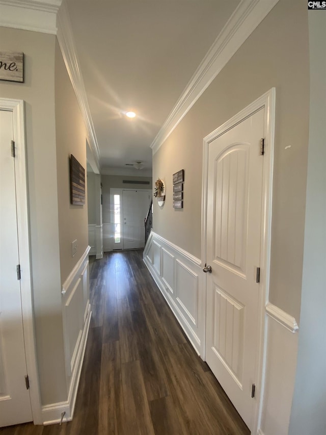 hall featuring dark wood finished floors, stairs, ornamental molding, wainscoting, and a decorative wall