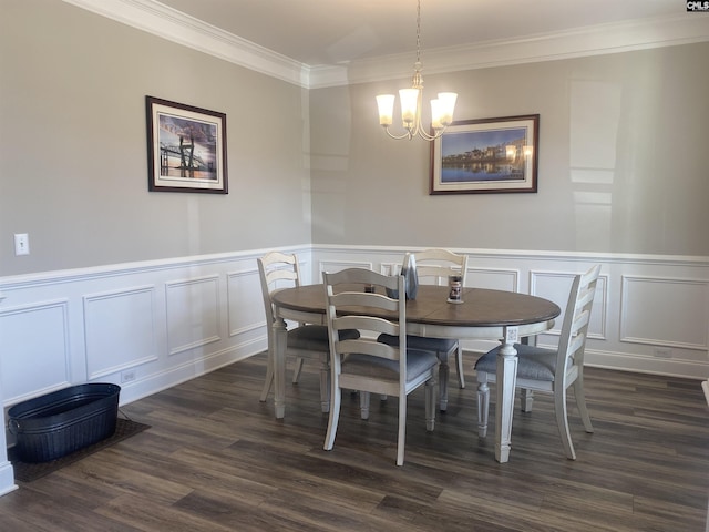 dining room featuring a wainscoted wall, a notable chandelier, dark wood finished floors, crown molding, and a decorative wall