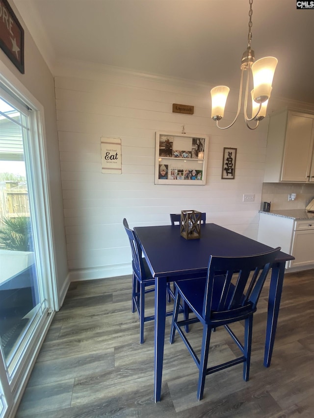 dining room with a chandelier, crown molding, dark wood-type flooring, and baseboards