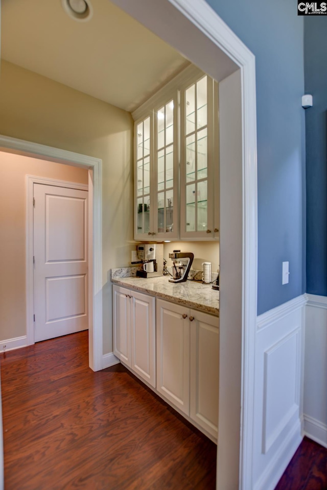 bar featuring dark wood-type flooring and a wainscoted wall