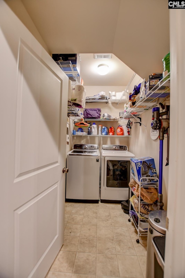 washroom featuring light tile patterned floors, visible vents, laundry area, and washing machine and clothes dryer