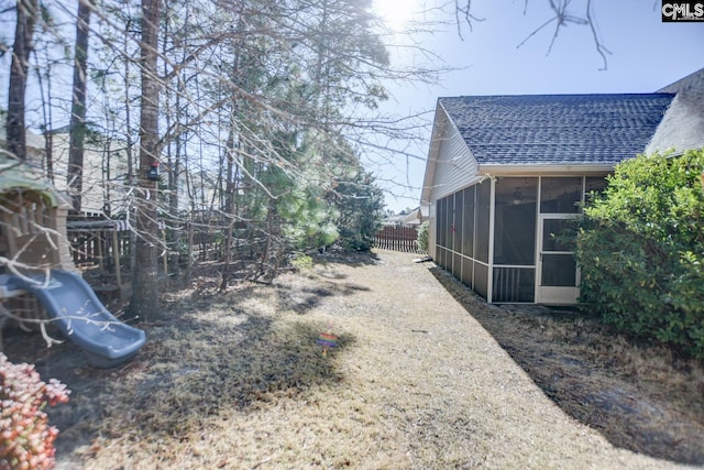 view of yard featuring a playground and a sunroom