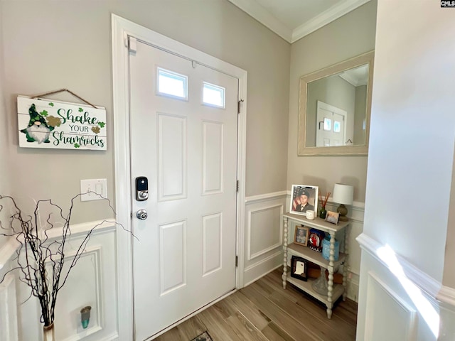 foyer featuring a wainscoted wall, wood finished floors, crown molding, and a decorative wall