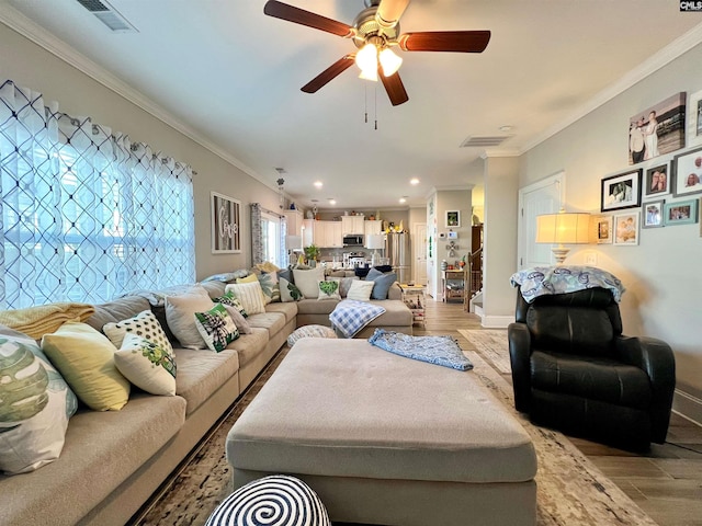 living area featuring crown molding, visible vents, light wood finished floors, and ceiling fan