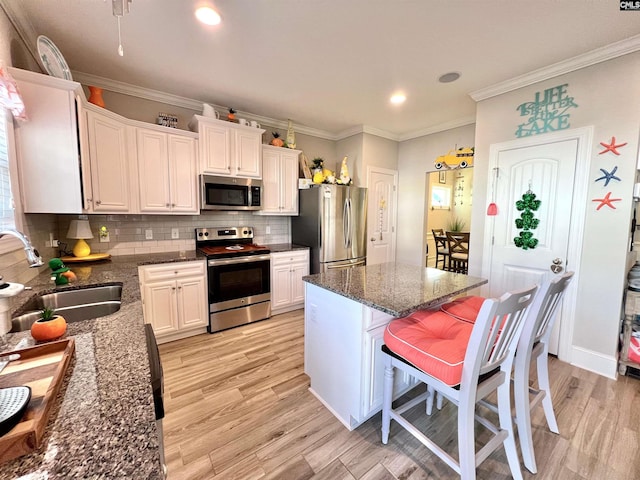 kitchen featuring light wood-type flooring, a sink, backsplash, a center island, and stainless steel appliances