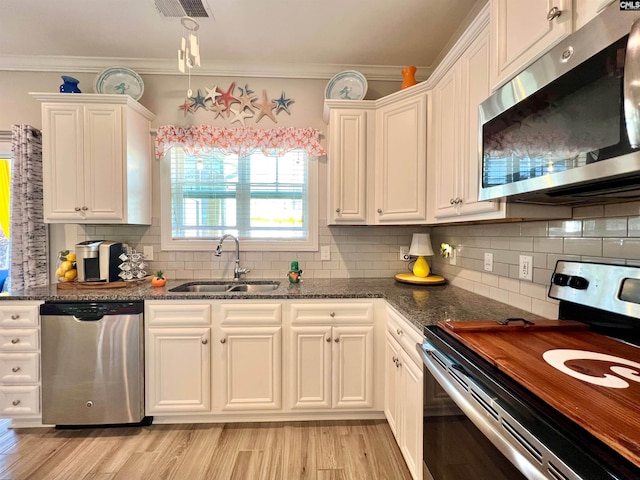 kitchen featuring visible vents, a sink, stainless steel appliances, white cabinets, and crown molding