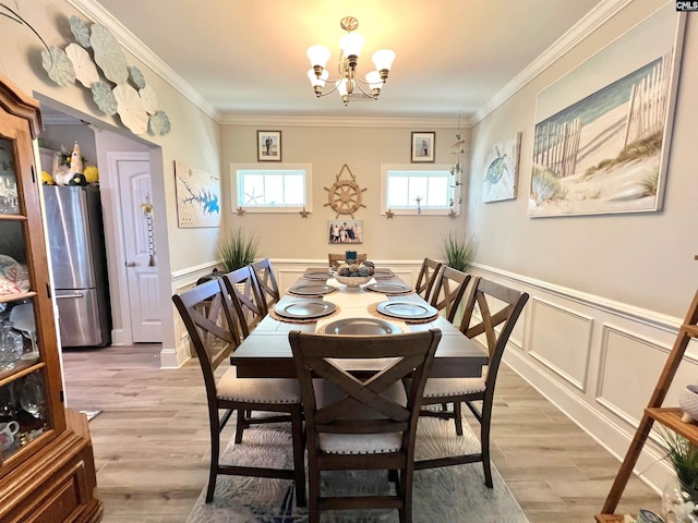 dining room with a notable chandelier, light wood finished floors, and ornamental molding