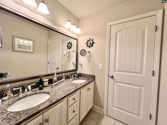 bathroom featuring tile patterned flooring, double vanity, baseboards, and a sink