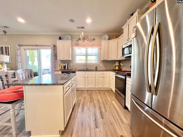 kitchen with visible vents, a sink, tasteful backsplash, a center island, and stainless steel appliances