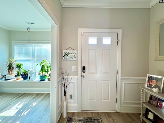 foyer with wood finished floors, visible vents, and ornamental molding