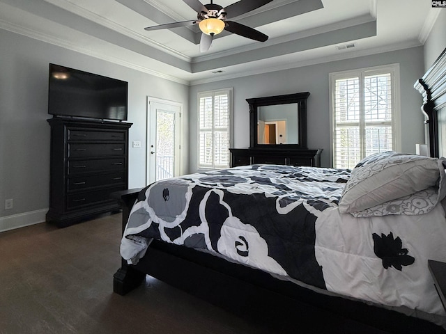 bedroom with a tray ceiling, multiple windows, visible vents, and crown molding