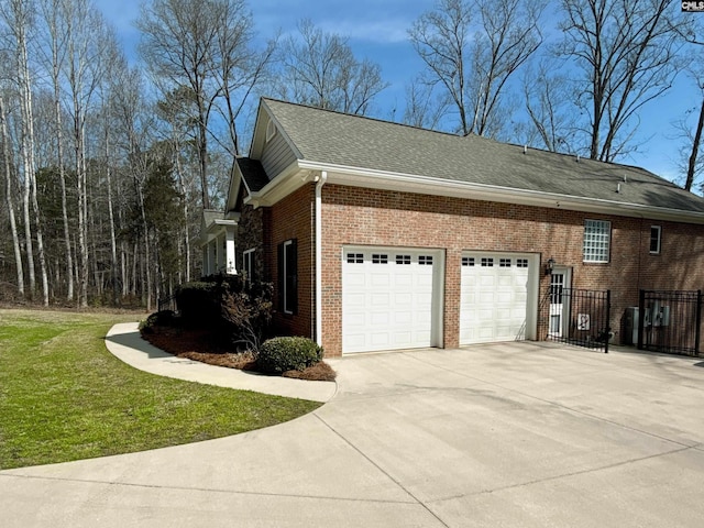 view of side of property featuring brick siding, a shingled roof, a yard, a garage, and driveway