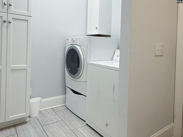 laundry area featuring cabinet space, washing machine and dryer, and baseboards