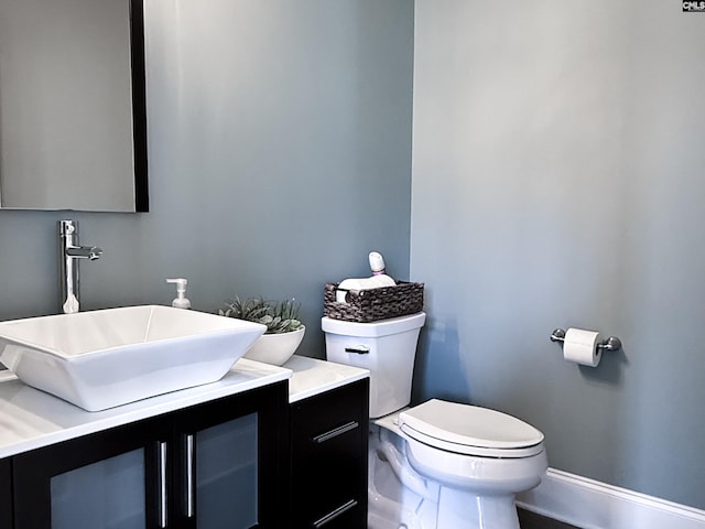 bathroom featuring baseboards, toilet, and vanity