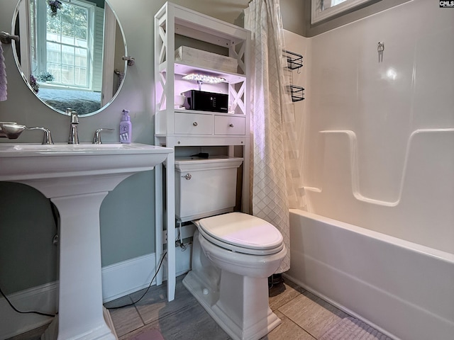 full bath with a sink, shower / bathtub combination with curtain, and toilet