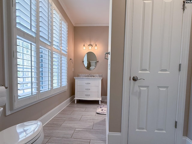 bathroom with vanity, baseboards, wood finish floors, ornamental molding, and toilet