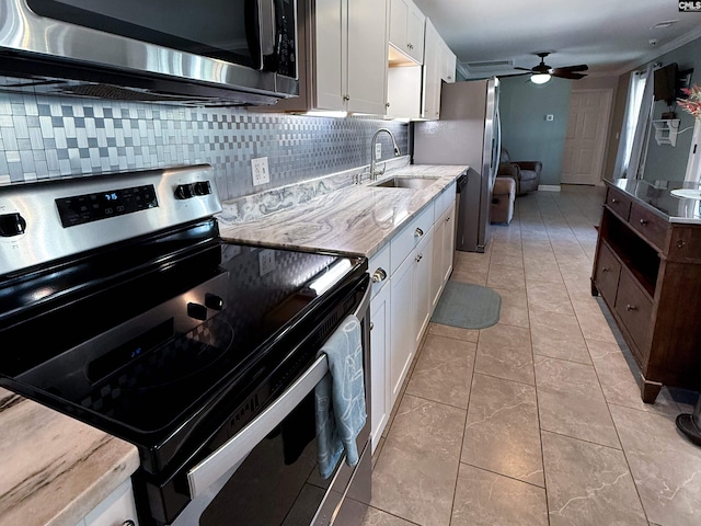 kitchen featuring a sink, decorative backsplash, ceiling fan, stainless steel appliances, and white cabinetry