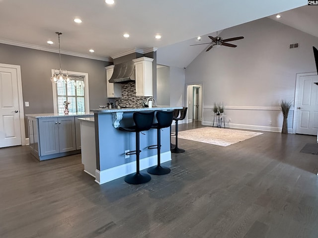 kitchen featuring dark wood finished floors, ceiling fan with notable chandelier, a peninsula, and a kitchen bar