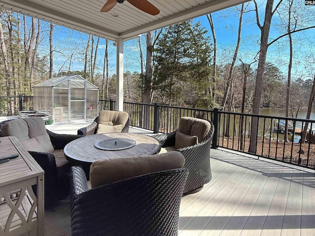 wooden terrace featuring an outbuilding, an exterior structure, an outdoor hangout area, and a ceiling fan