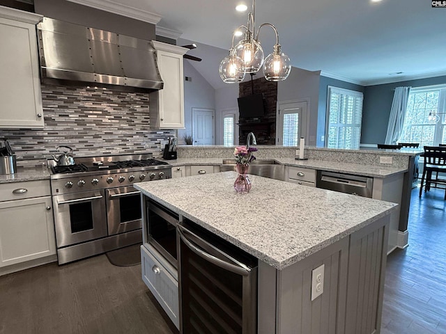 kitchen featuring beverage cooler, a sink, a kitchen island, range hood, and stainless steel appliances