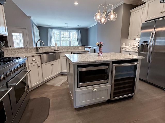 kitchen featuring beverage cooler, ornamental molding, appliances with stainless steel finishes, and a sink