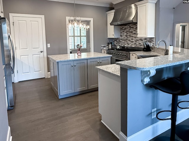 kitchen featuring a kitchen island, a sink, decorative backsplash, appliances with stainless steel finishes, and wall chimney exhaust hood