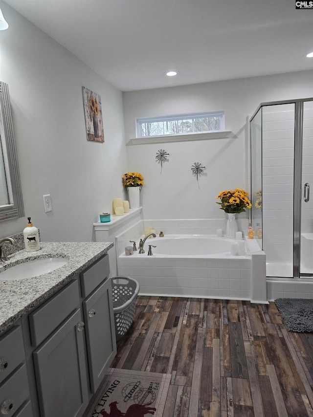 full bath with recessed lighting, a stall shower, wood finished floors, a bath, and vanity