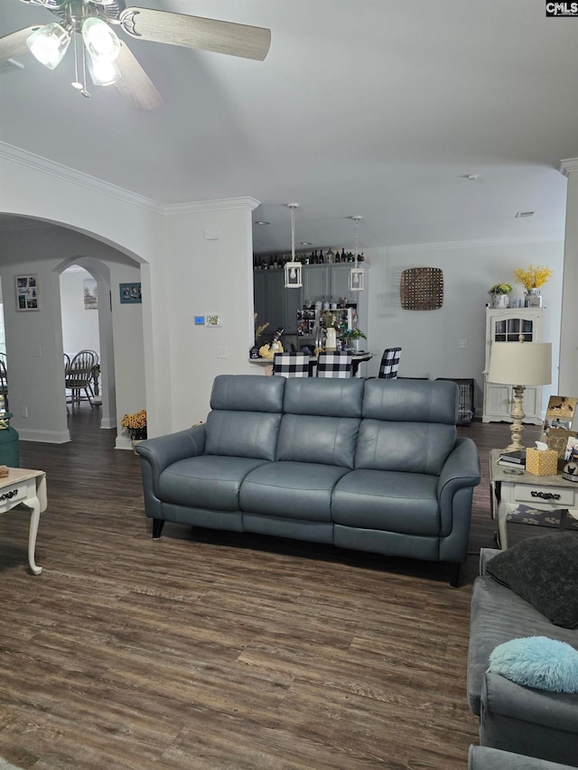 living room with crown molding, wood finished floors, a ceiling fan, and arched walkways