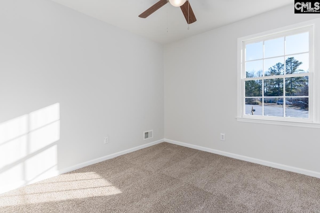 carpeted spare room featuring a ceiling fan, visible vents, and baseboards