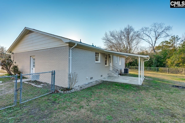 exterior space with brick siding, fence, a lawn, cooling unit, and a patio