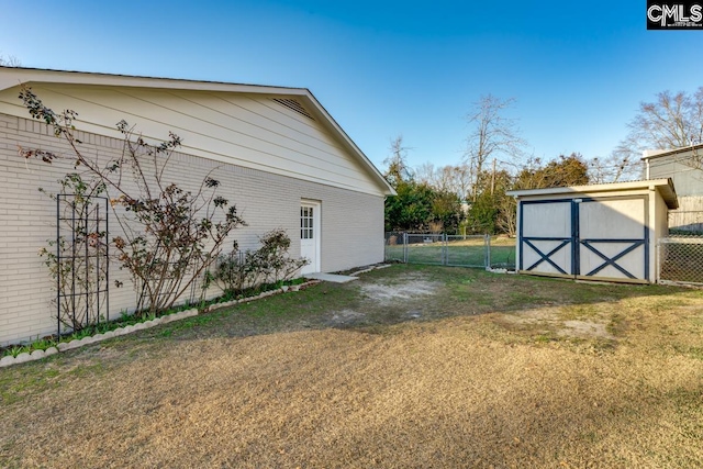 view of yard featuring an outbuilding, a storage shed, a gate, and fence