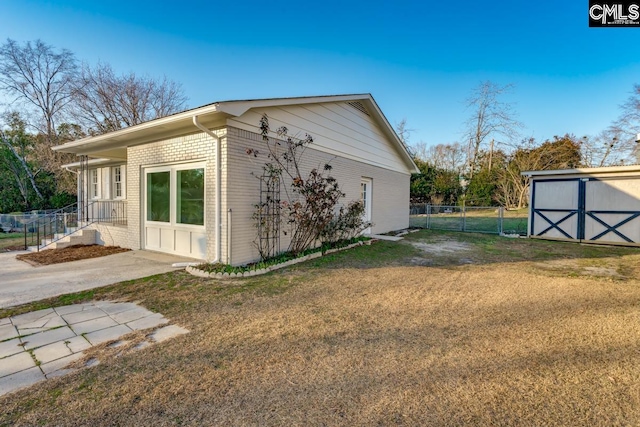 view of side of property featuring an outbuilding, fence, a yard, a storage shed, and brick siding