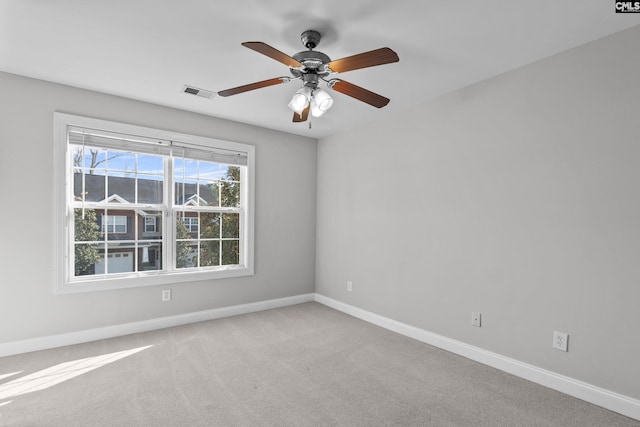 spare room with visible vents, light colored carpet, a ceiling fan, and baseboards