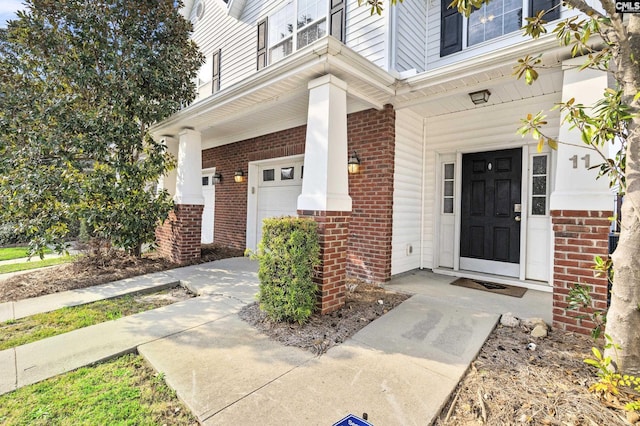 doorway to property with a garage and brick siding