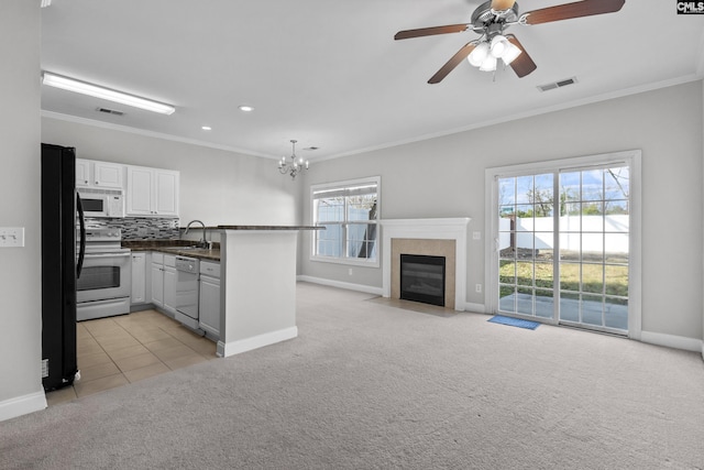 kitchen featuring dark countertops, visible vents, crown molding, light carpet, and white appliances