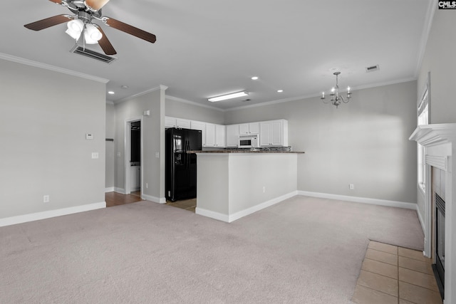 kitchen featuring light colored carpet, white microwave, visible vents, and black fridge