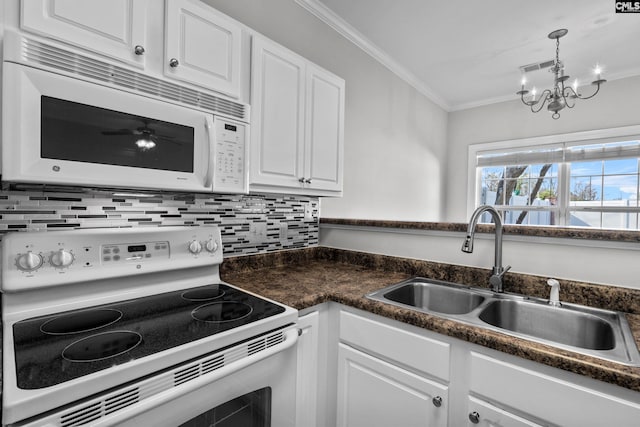 kitchen with dark countertops, white appliances, crown molding, and a sink