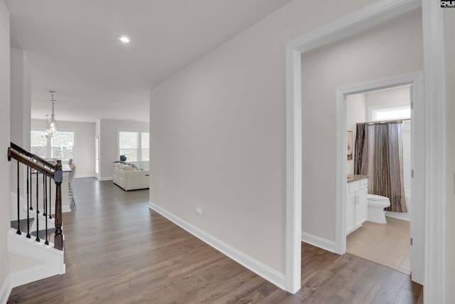 corridor featuring recessed lighting, baseboards, wood finished floors, and stairs