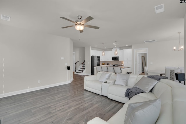 living area featuring visible vents, ceiling fan with notable chandelier, and wood finished floors