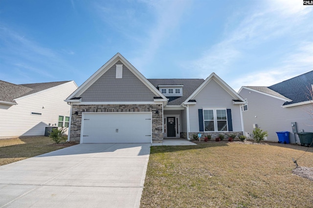 craftsman-style house with a shingled roof, a front yard, driveway, stone siding, and an attached garage