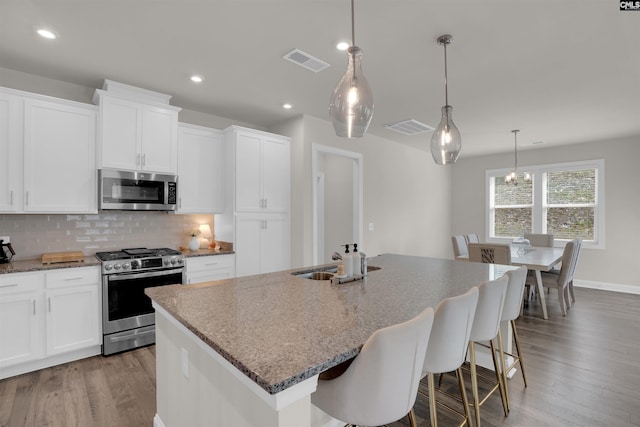 kitchen with visible vents, tasteful backsplash, appliances with stainless steel finishes, and wood finished floors