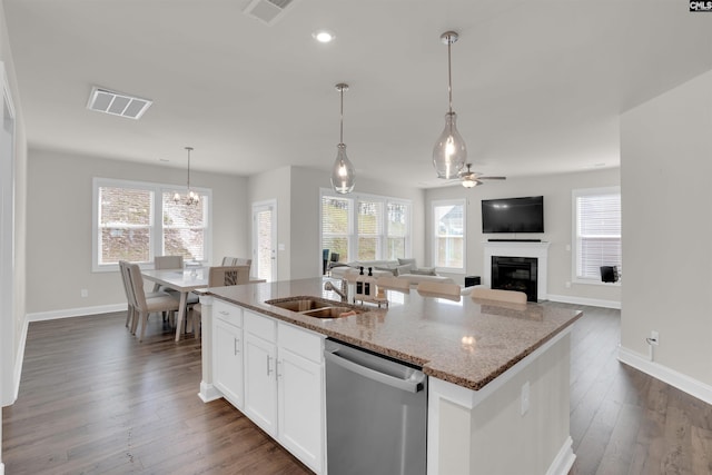 kitchen featuring dishwasher, a glass covered fireplace, visible vents, and a sink