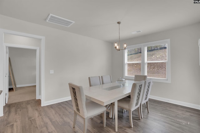 dining space with a chandelier, visible vents, baseboards, and wood finished floors