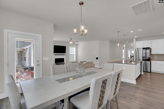 dining area featuring recessed lighting, visible vents, ceiling fan with notable chandelier, and wood finished floors