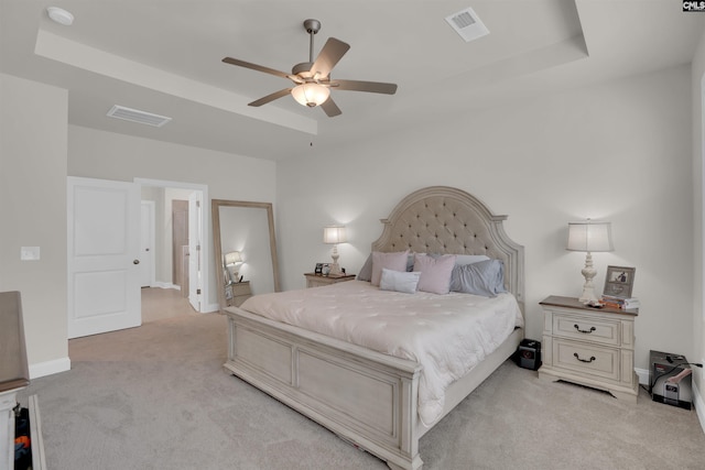 bedroom with visible vents, light colored carpet, baseboards, and a tray ceiling