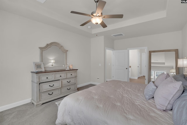 bedroom with baseboards, a raised ceiling, light carpet, and visible vents