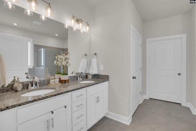 bathroom with double vanity, baseboards, a stall shower, and a sink